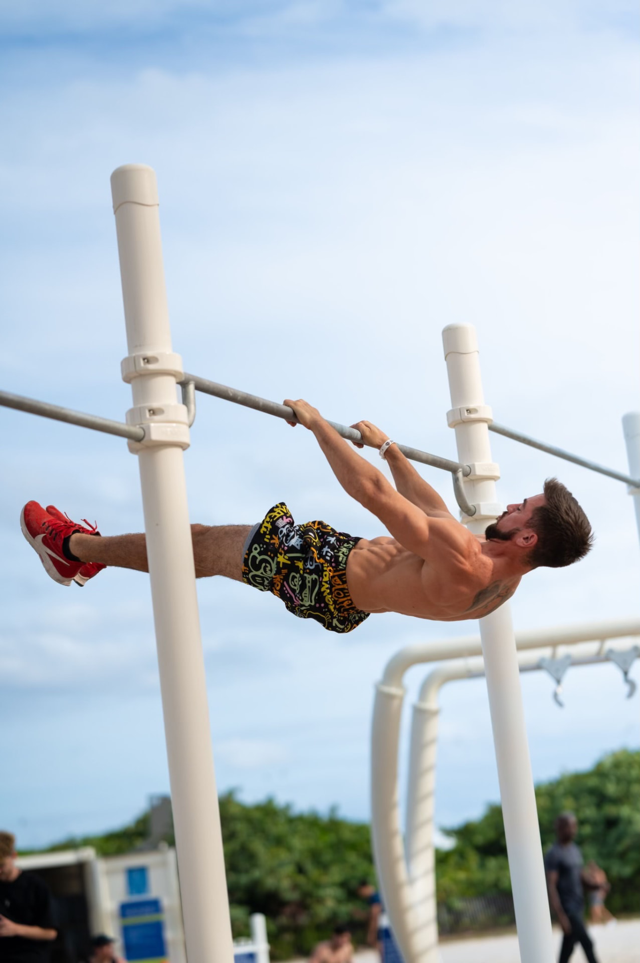 Front lever hold on a straight bar at the beach