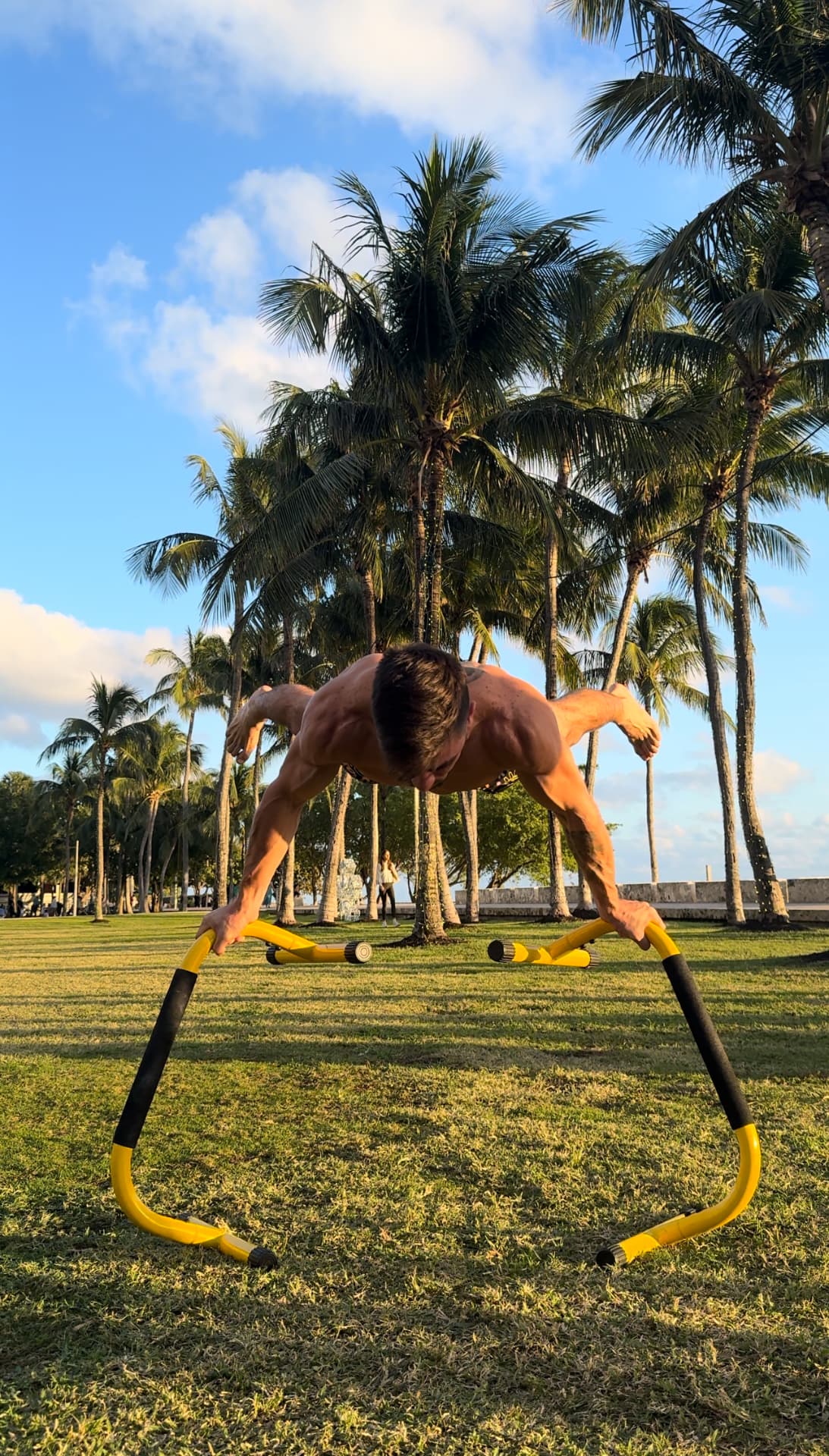 Full planche on yellow parallettes at sunset