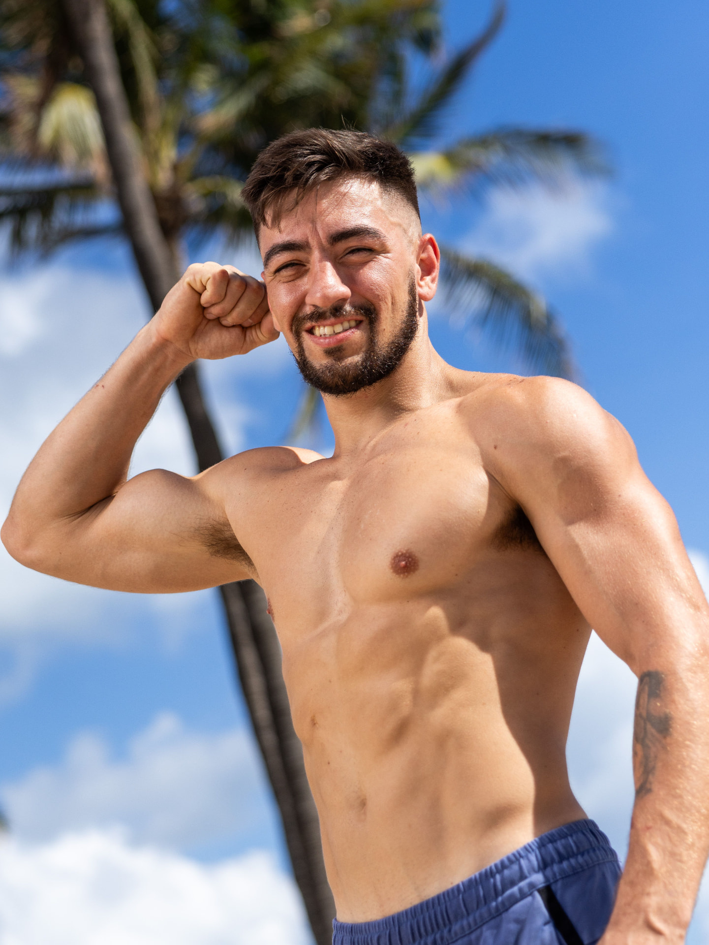 Coach flexing under the palms after a session
