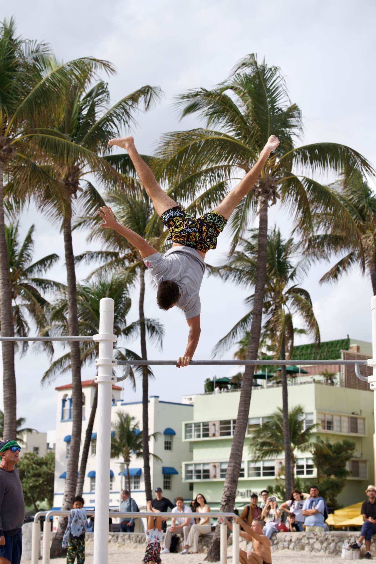 One-arm handstand on a high bar under palm trees